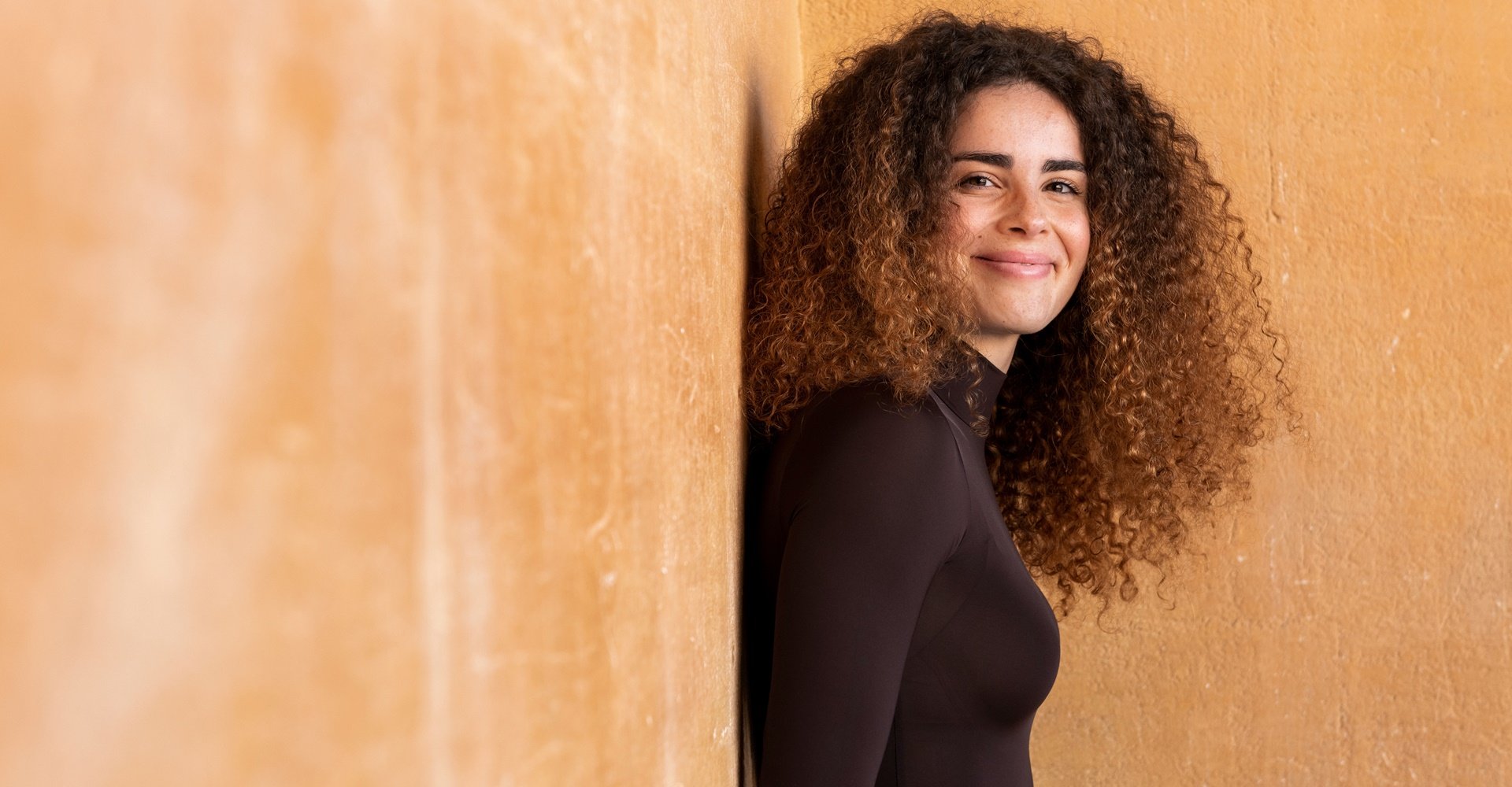 mulher com cabelo cacheado com pontas morena iluminada
